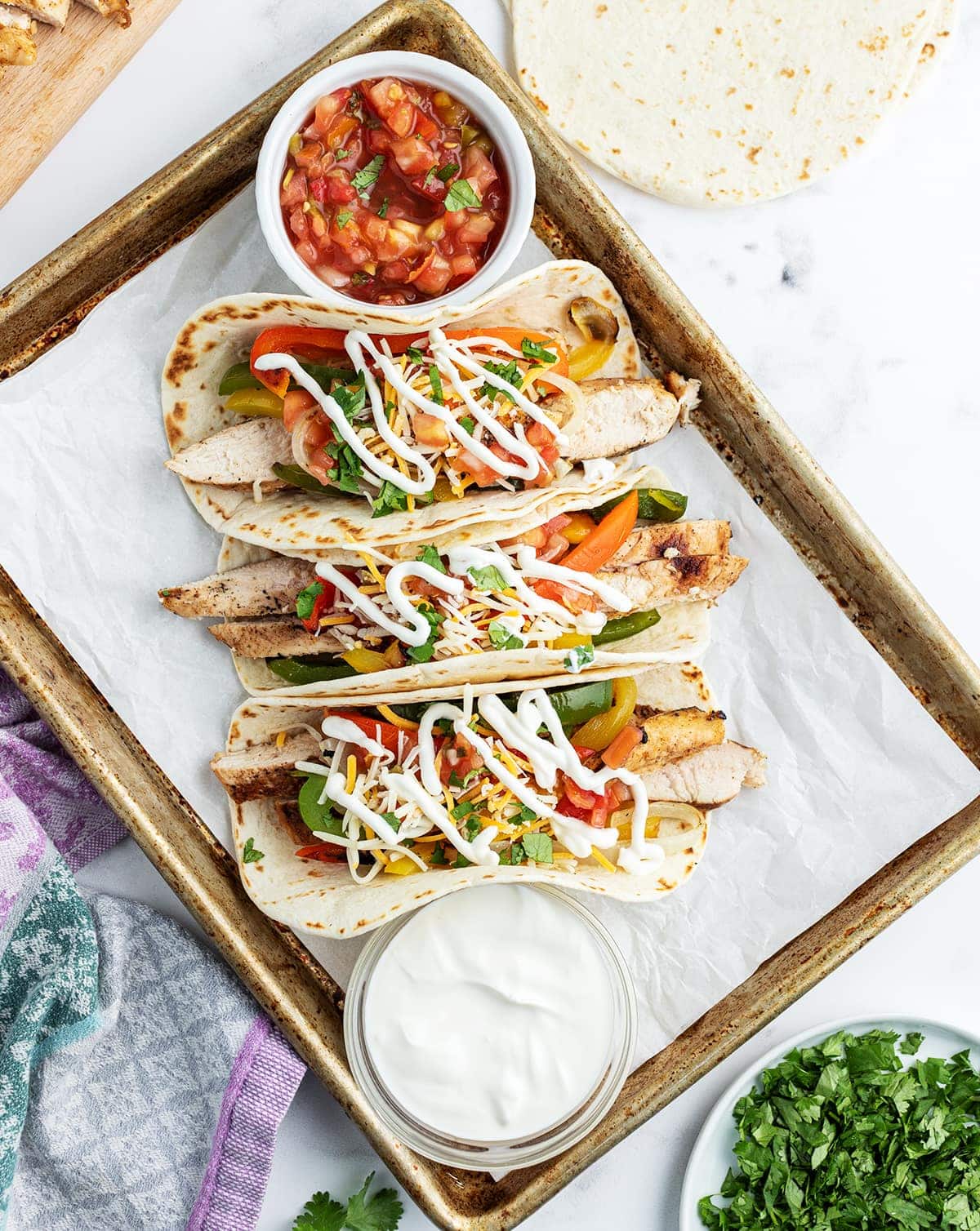 Chicken fajitas in warm tortillas with peppers, cheese, sour cream, and salsa